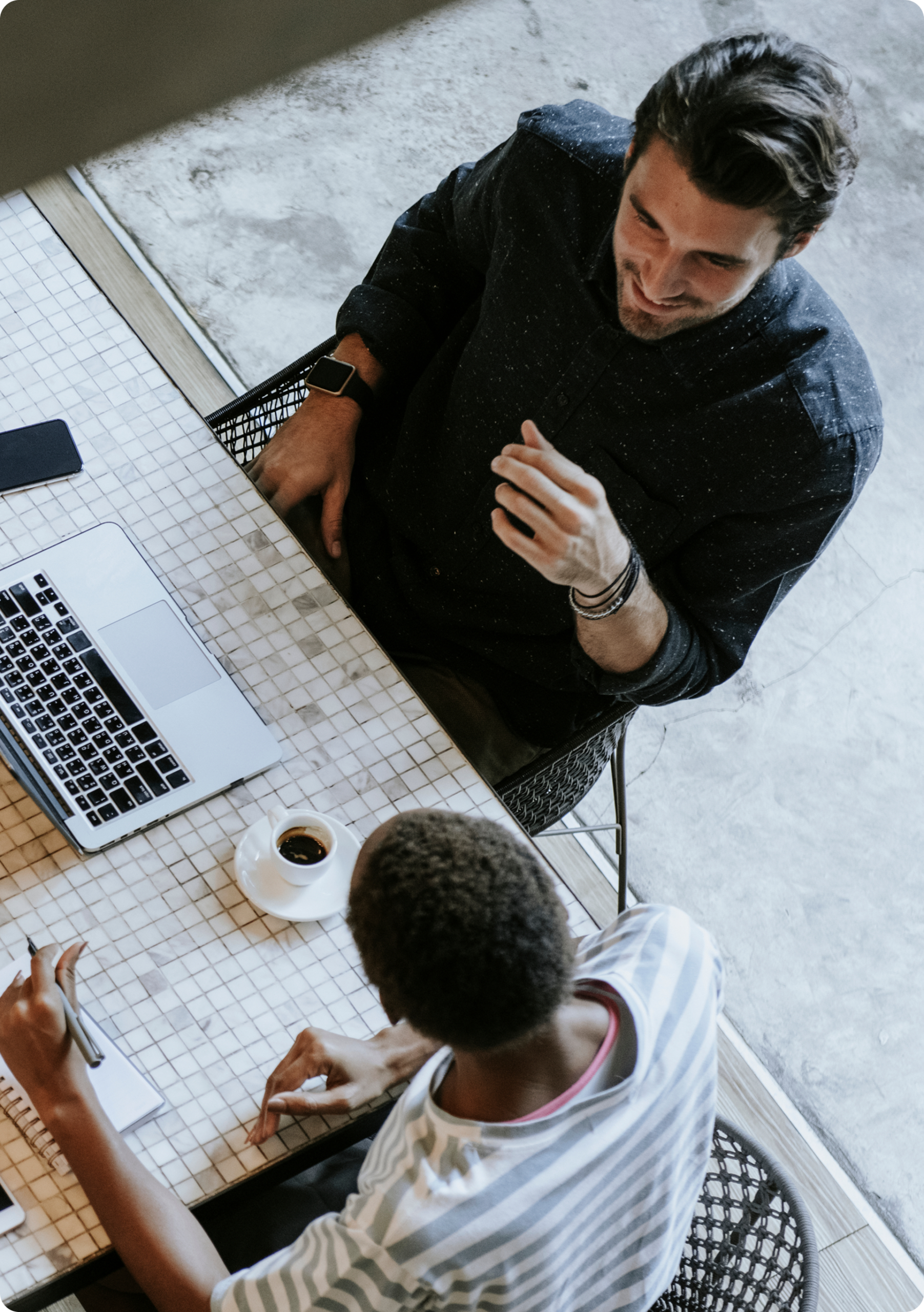 Overhead view of two colleagues discussing work at a table