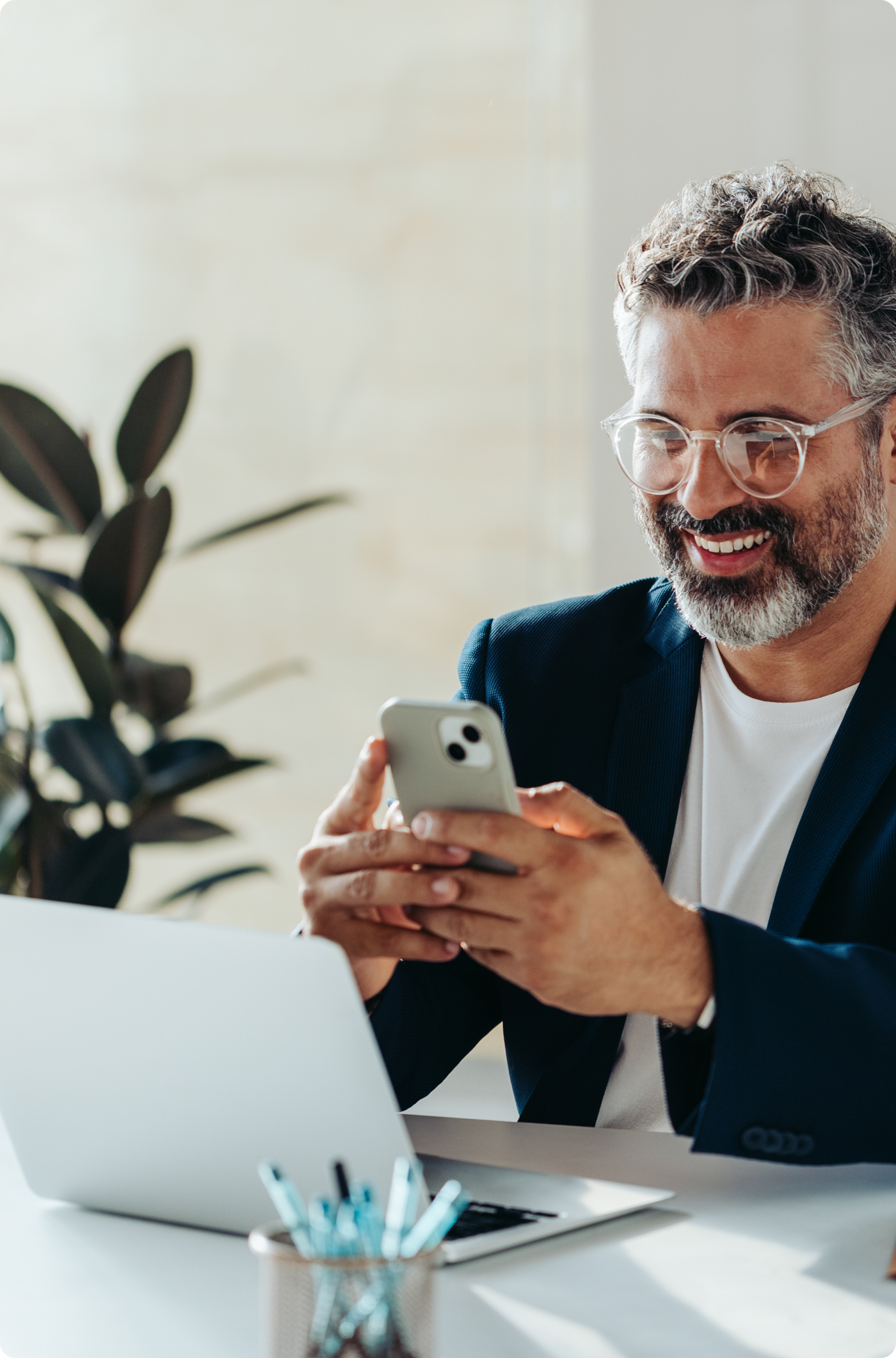 Man using a smartphone beside an open laptop
